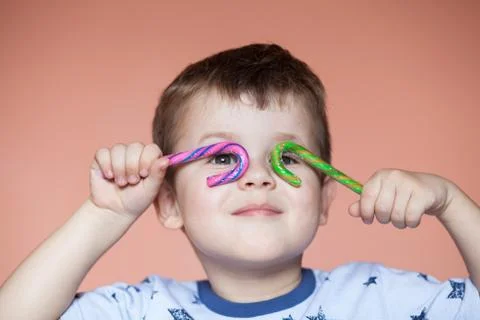 A cute boy holding two candy sticks. Stock Photos