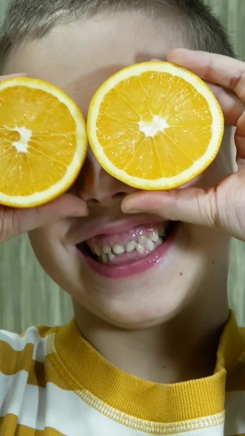 A cute boy holds halves of a lemon near his face Stock Footage 314094419