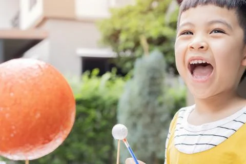 Cute boy laughing while creating his homemade solar system and painting plane Stock Photos