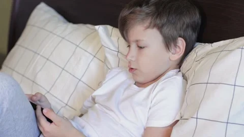 Cute boy laying on bed and playing on mobile phone Stock Footage 159172255