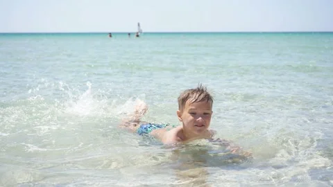 Cute boy learn to swim in the crystal clear sea in shallow water Vídeos de archivo 140097115