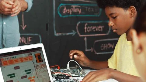 Cute boy learning to use electronic tool while laptop display code. Edification. Stock Photos