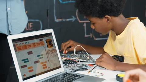 Cute boy learning to use electronic tool while laptop display code. Edification. Foto stock