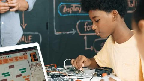 Cute boy learning to use electronic tool while laptop display code. Edification. Stock Photos
