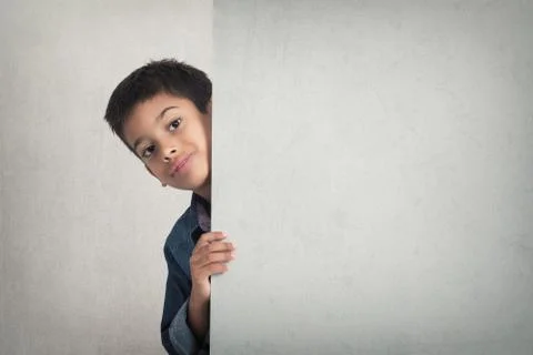 Cute boy looking from behind blank advertising board Stock Photos