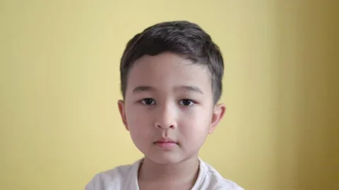 Cute boy looking at camera and looks very sad on colour background Stock Footage 195037565