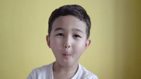 Cute boy looking at camera and grimaces on colour background Stock Footage 195037930
