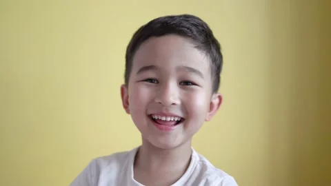 Cute boy looking at camera and laughing on colour background Stock Footage 195038089