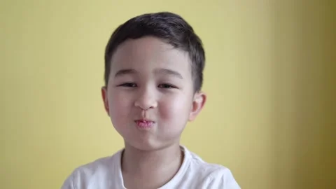 Cute boy looking at camera and grimaces on colour background Stock Footage 195039355