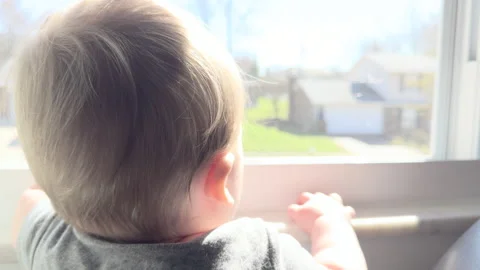 Cute boy looking out window turns around 4k Stock Footage 332957580