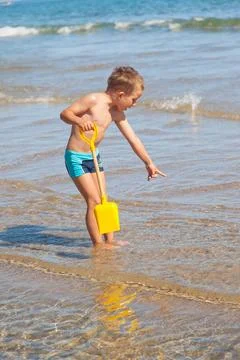 Cute boy looking for sea shells on the beach Cute boy looking for sea shel... Stock Photos