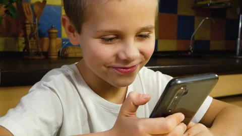 Cute boy looking at smartphone screen and smiling. Communication in messengers. Stock Footage 255460190