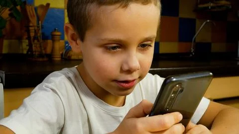 Cute boy looking at smartphone screen and talking. Communication with the help Stock Photos