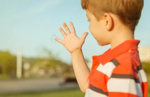 Cute boy looking soap bubble in his open hand Stock Photos