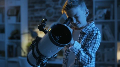 Cute boy looking at the stars through a telescope at night Stock Footage 128499716