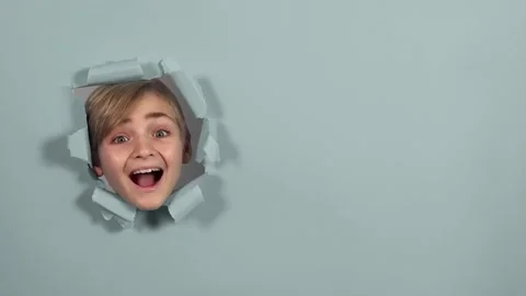 Cute boy looking through the hole on gray paper and screaming. Copy space. Stock Footage 164676114