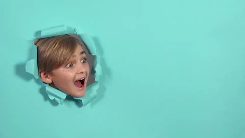 Cute boy looking through the hole on blue paper and surprising. Copy space. Stock Footage 164676123