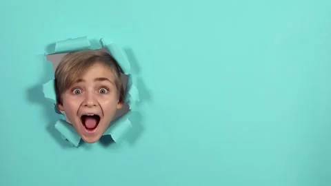 Cute boy looking through the hole on blue paper and screaming. Copy space. Stock Footage 164676124