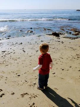 Cute boy looking at waves at the beach Stock Photos