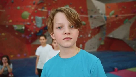 A cute boy looks at the camera with a calm gaze while inside the climbing wall Stock Footage 275329755
