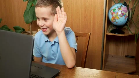 A cute boy old sits at home in front of a laptop during an online lesson raises Stock Footage 230651981