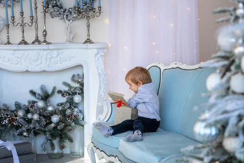 A cute boy opens a gift box in a New Year's atmosphere Fotos Stock