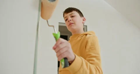 Cute boy with a paint roller. Kid helps parents to paint wall. Repair of a new Stock Footage 273201741