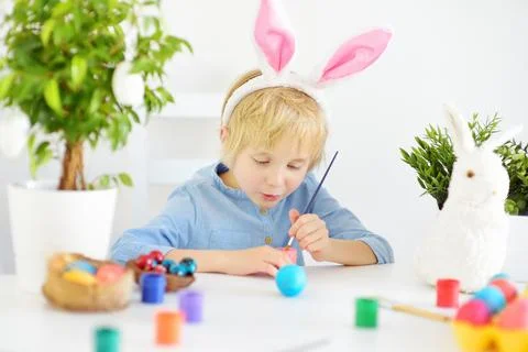 Cute boy paints eggs for Easter holiday. Stock Photos
