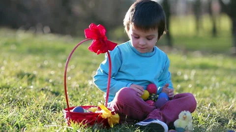 Cute boy in the park, having fun with colored eggs for Easter, springtime Stock Footage 47568531