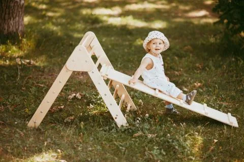 Cute boy performs gymnastic exercises on a wooden home sports complex stairs. Stock Photos