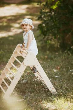 Cute boy performs gymnastic exercises on a wooden home sports complex stairs. Fotos Stock