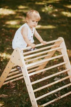 Cute boy performs gymnastic exercises on a wooden home sports complex stairs. Stock Photos