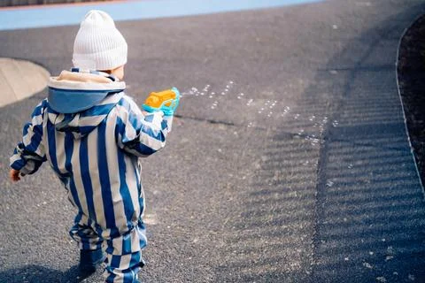 Cute boy play with soap bubbles holding bubble gun it the playground Stock Photos