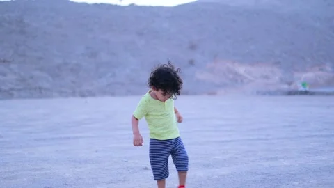 Cute boy playing alone at the top of a mountain he is wearing yellow dress Stock Footage 159661181