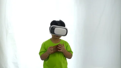 Cute a boy playing game by smartphone and wearing VR goggles on white background Stock-Footage 95996982