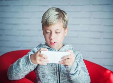 Cute boy playing with a smartphone Stock Photos