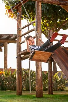 Cute boy playing on swing, having fun. Sunset in the park. Photos