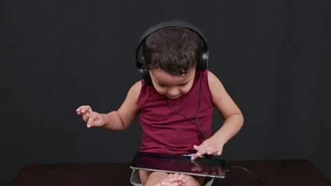 Cute boy playing with tab and headphone isolated in black background Stock Footage 160549585