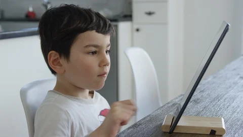 Cute boy playing tablet at the table at the white kitchen 4K RED Footage Stock-Footage 129053843
