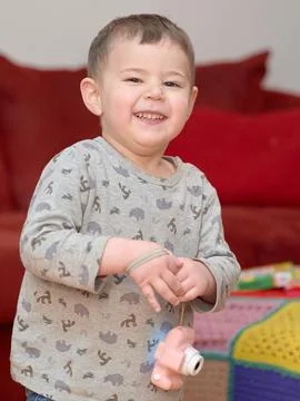Cute boy playing with a toy camera while watching tv at home by the couch Stock Photos