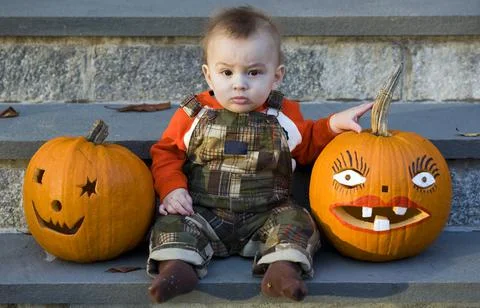 Cute boy posing with two painted pumpkins Stock Photos