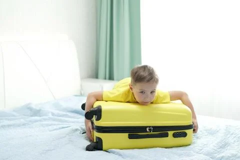 Cute boy put his head on a yellow travel suitcase. He was going on a trip to the Stock Photos