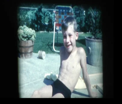 Cute boy relaxing poolside looks to camera Stock Footage 33843873