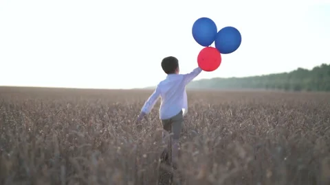Cute boy running in the wheat field with balloons Stock Footage 157285504