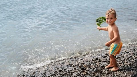 A cute boy runs along the seashore, along the beach. Outdoor activities. Stock Photos