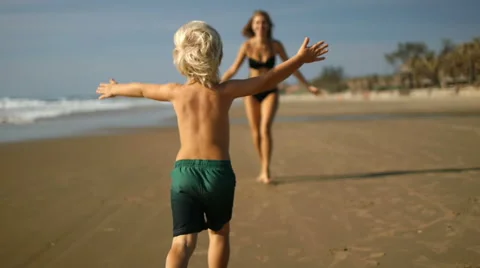 A cute boy runs a long the beach to her mother Stock Footage 49671736
