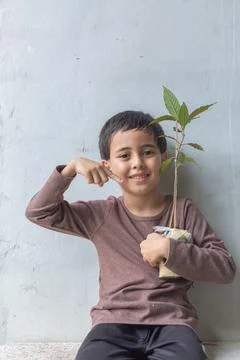 A cute boy sat hugging a tree on his chest. Stock Photos