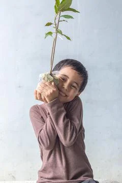 A cute boy sat hugging a tree on his chest. Stock Photos
