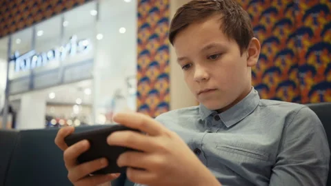 Cute boy sits on the sofa in the mole hall and plays emotionally in a game on Stock Footage 97851267
