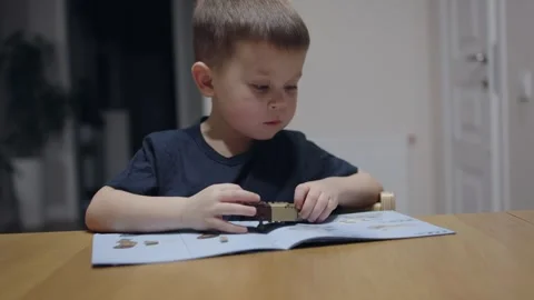 Cute boy sits at table playing educational toy construction set following Video stock 277000918